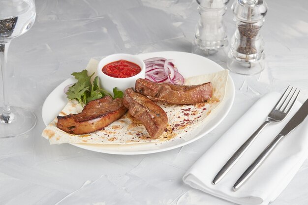 Gegrilltes Fleisch auf einem Teller, das in einem Restaurant, heller Hintergrund dient