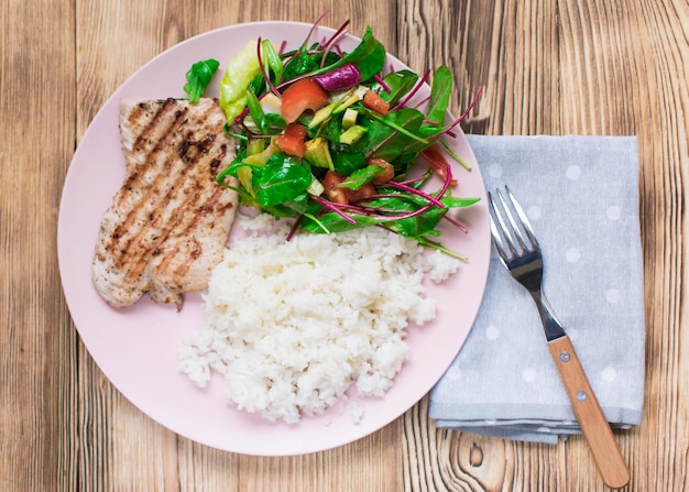 Gegrilltes Fleisch, gekochter Reis und Gemüsesalat auf Holzhintergrund