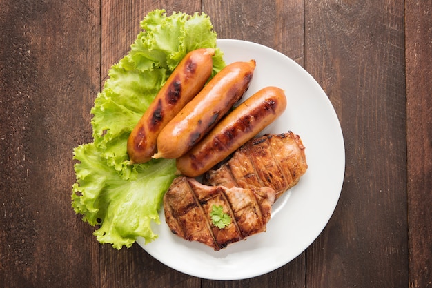 Gegrilltes Fleisch, Würstchen und Gemüse auf Teller.