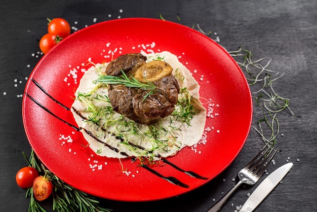 Gegrilltes Fleischsteak auf Pita-Blatt in einer roten Platte