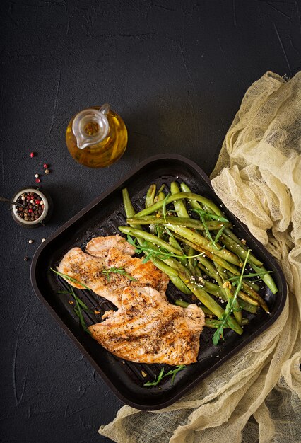 Gegrilltes Fleischsteak mit Bohnen auf dunklem Teller, Draufsicht