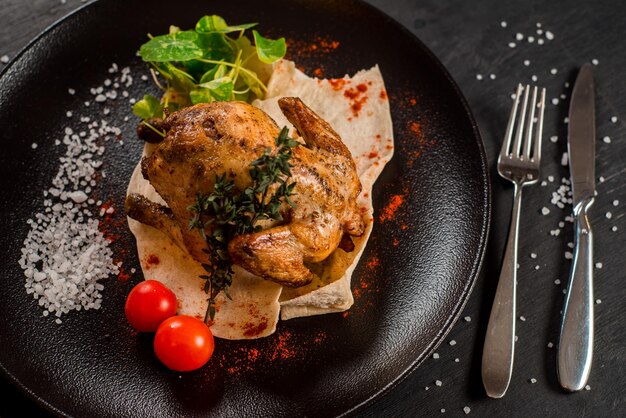 Gegrilltes ganzes Huhn mit Gemüse auf schwarzem Hintergrund