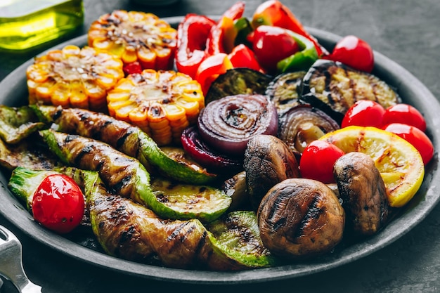 Gegrilltes Gemüse in Schüssel auf dunklem Stein Hintergrund Zucchini-Paprika Mais Tomaten rote Zwiebeln und Auberginen