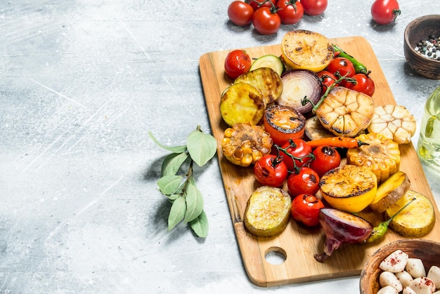 Gegrilltes Gemüse mit Gewürzen und Kräutern auf einem Schneidebrett