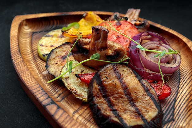 Gegrilltes Gemüse mit Pilzen auf einem Holzbrett