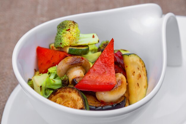 Gegrilltes Gemüse mit Pilzen auf einem Teller auf hellem Hintergrund