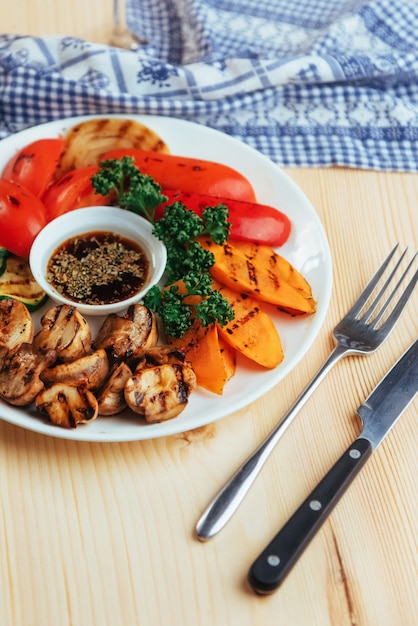 Gegrilltes Gemüse mit Soße auf einem Holztisch