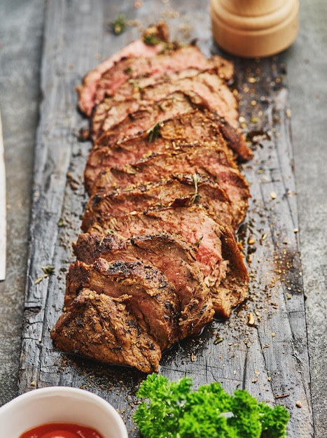 Gegrilltes geschnittenes Rindersteak auf Schneidebrett über grauem Tisch Rinderfiletsteak Filet Mignon Rezept