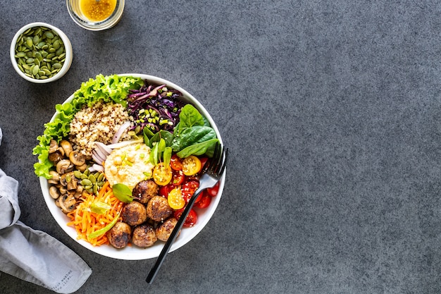 Gegrilltes Hähnchen, Reis, würzige Kichererbsen, Avocado, Kohl, Pfeffer-Buddha-Schüssel auf dunkler Oberfläche, Draufsicht. Köstliches ausgewogenes Lebensmittelkonzept