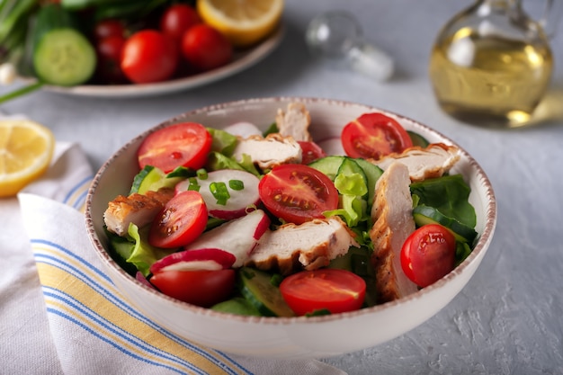 Gegrilltes Hähnchenbrustfilet und frischer Gemüsesalat aus Salat, Spinat, Gurke und Tomate