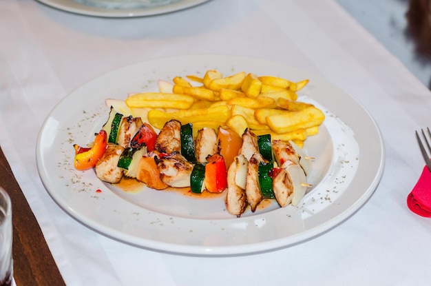 Gegrilltes Hühnchen-Shashlik mit Pommes Frites serviert