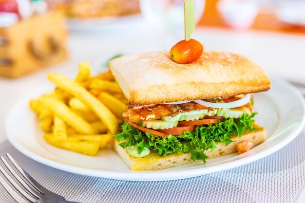 Foto gegrilltes lachs- und speck-sandwich mit pommes frites auf einem weißen teller