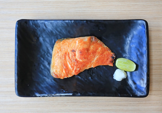 Gegrilltes Lachsfiletsteak mit Salz auf schwarzem Tablett serviert. Japanische Küche.