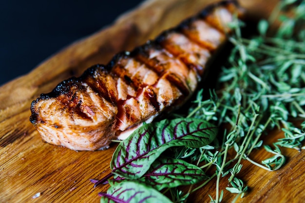 Gegrilltes Lachsfischfilet mit grünem Salat auf dem Holzschneidebrett hautnah