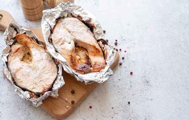 Gegrilltes Lachssteak auf hölzernem Schneidebrett auf Draufsicht des konkreten Hintergrundes Beschneidungspfad eingeschlossen