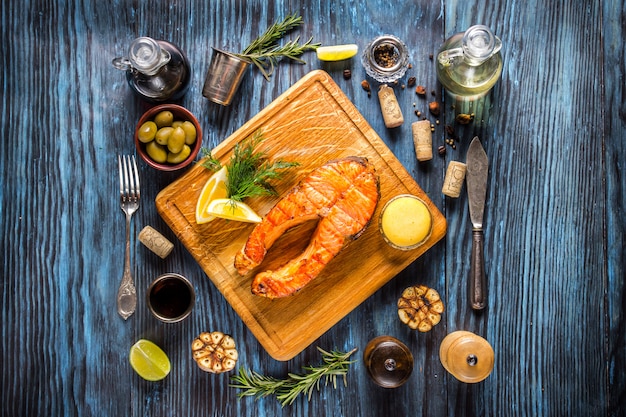 Gegrilltes Lachssteak mit Zitrone auf rustikalem hölzernem Hintergrund.