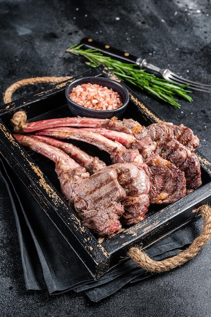 Gegrilltes Lammkotelett Steak Hammelfleisch Schnitzel in Holzschale Schwarzer Hintergrund Draufsicht