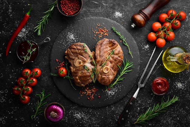 Gegrilltes Lammsteak mit Gewürzen und Rosmarin Grillfleisch Draufsicht Flache Draufsicht auf Schneidetisch aus schwarzem Stein