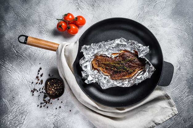 Gegrilltes Lendensteak in Folie. Schwarzer Hintergrund. Draufsicht