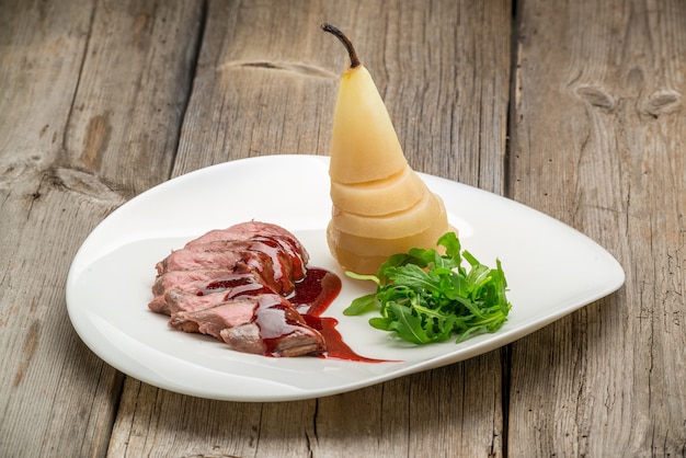 Gegrilltes mittleres seltenes Rindfleisch mit Birne, gegrilltes Gemüse, auf hölzernem Hintergrund schließen oben.