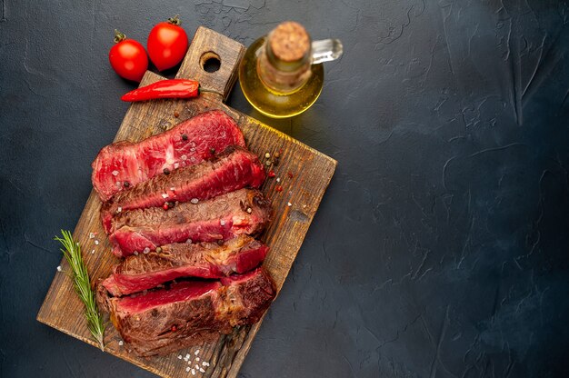 Gegrilltes Rib-Eye-Rindersteak mit Kräutern und Gewürzen auf Steinhintergrund mit Kopierraum für Ihren Text