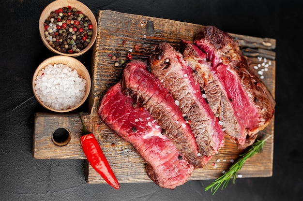 Gegrilltes Rib-Eye-Rindersteak mit Kräutern und Gewürzen auf Steinhintergrund