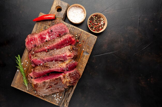 Gegrilltes Rib-Eye-Rindersteak mit Kräutern und Gewürzen auf Steinhintergrund