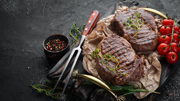 Gegrilltes Ribeye Beefsteak Kräuter und Gewürze auf einem dunklen Tisch Draufsicht Freier Platz für Ihren Text