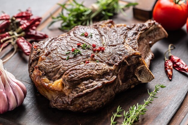 Gegrilltes Rindersteak mit Gewürzkräutern, Salzpfeffer und Knoblauch auf Holzbrett.