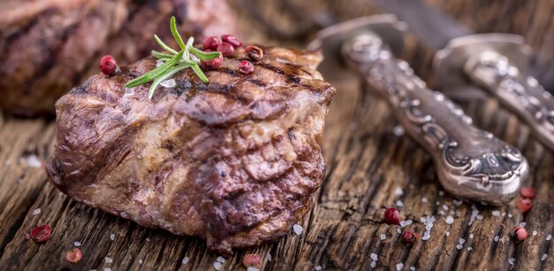 Gegrilltes Rindersteak mit Rosmarin, Salz und Pfeffer auf altem Schneidebrett. Rinderfiletsteak.