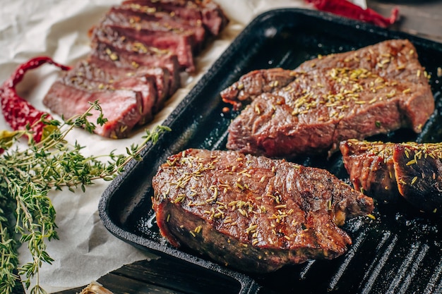 Gegrilltes Rindfleischsteak auf Bratpfanne, Draufsicht. Gebratene Fleischstücke hautnah