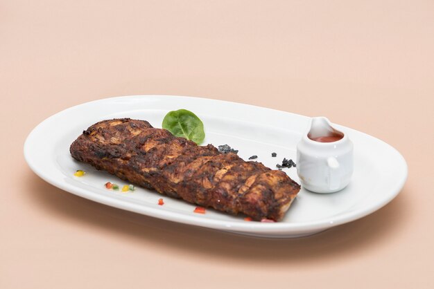 Gegrilltes Rippenschweinefleisch mit Barbecue-Sauce, platziert auf weiße Platte, heller Hintergrund