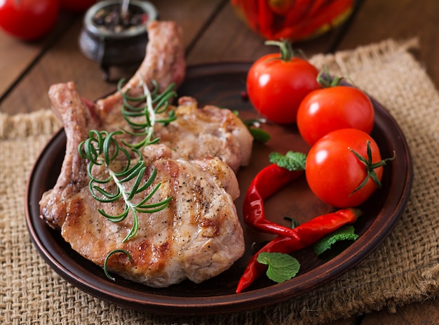 Gegrilltes saftiges Steak mit Knochen mit Gemüse auf einem hölzernen Hintergrund.