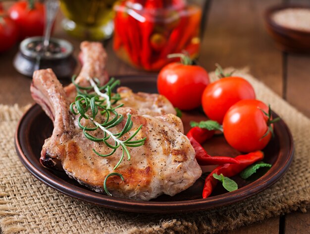 Gegrilltes saftiges Steak mit Knochen mit Gemüse auf einem hölzernen Hintergrund.