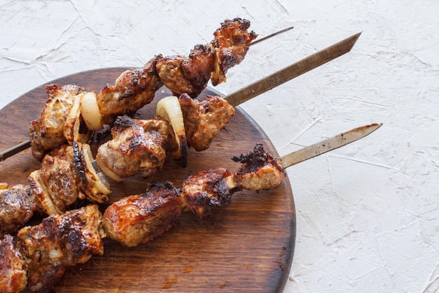 Gegrilltes Schweinefleisch auf Metallspießen gebraten auf einem Grill auf Holzschneidebrett Ansicht von oben