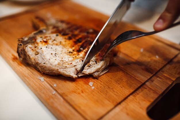 Gegrilltes Schweinefleisch mit Messer schneiden