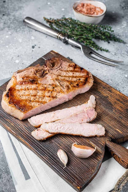 Gegrilltes Schweinefleisch oder T-Bone-Fleischsteak auf einem Holzbrett geschnitten Grauer Hintergrund Top-View