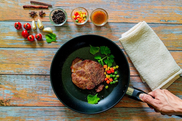 Gegrilltes Schweinesteak in der Pfanne auf schwarzem Hintergrund mit Kopienraum Draufsicht