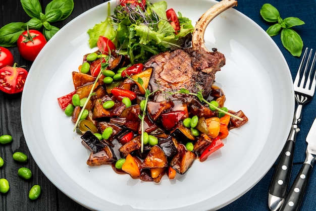 Gegrilltes Schweinesteak mit einem Knochen in einer süßen Honigglasur und Gemüseeintopf mit grünen Bohnen