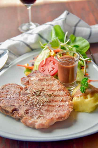 Gegrilltes Schweinesteak mit Kartoffelpüree auf einer Teller-Nahaufnahme.