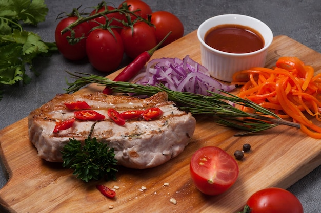 Gegrilltes Schweinesteak mit roten Zwiebeln, Karotten und Tomatensauce