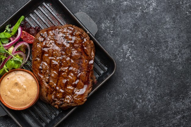 Gegrilltes Schweinesteak mit Sauce und Gemüse in einer Pfanne mit Platz für Text