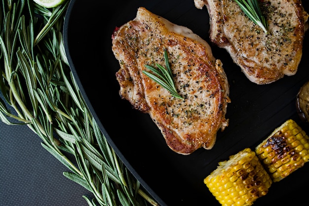 Gegrilltes Steak mit Gemüse in einer Pfanne mit Rosmarin dekoriert.