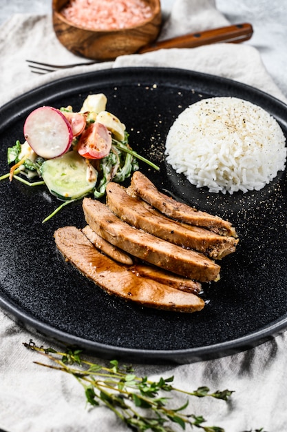 Gegrilltes Steak mit Hühnerbrust, garniert mit Reis. Grauer Hintergrund. Draufsicht