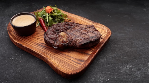 Gegrilltes Steak mit Sauce und Kräutern auf einem Holzbrett