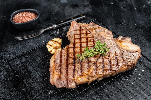 Gegrilltes Tbone- oder Porterhouse-Rindfleisch Steak auf einem Gestell Schwarzer Hintergrund Draufsicht
