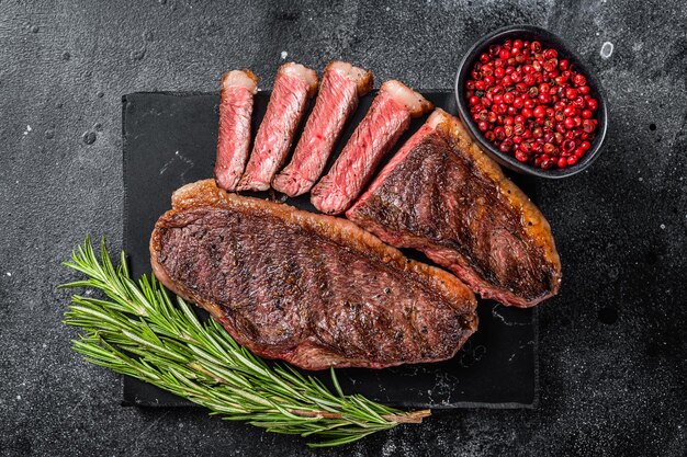 Gegrilltes Top Sirloin oder Cup Rump Beefsteak auf Marmorplatte Schwarzer Hintergrund Draufsicht