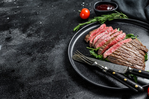 Gegrilltes und geschnittenes Flankensteak. Marmorfleisch. Schwarzer Hintergrund. Draufsicht. Speicherplatz kopieren.