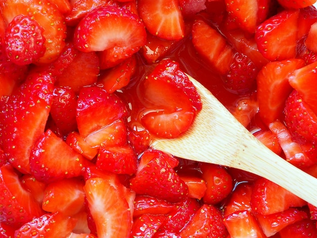 Gehackte Erdbeeren in Zuckersirup Holzlöffel Ansicht von oben