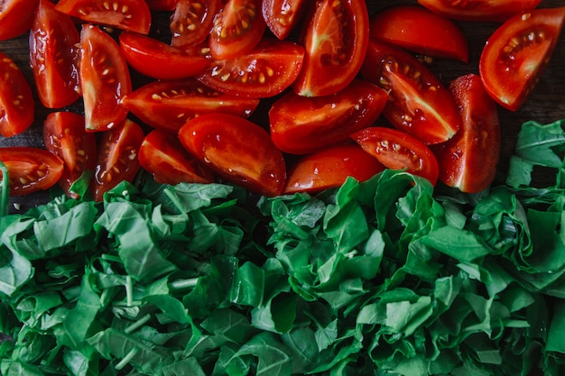 Foto gehackte tomaten und hellgrüner spinat auf rustikalem holztisch, draufsicht.